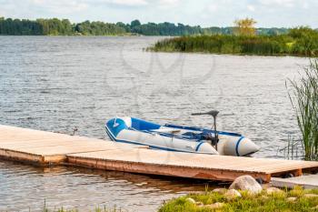 Inflatable boat with a motor tied to a wooden pier