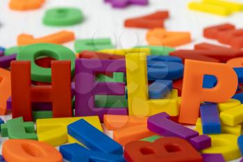 Plastic colored letters spelling word HELP. Close-up view.