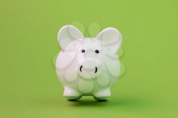 White ceramic piggy bank on green background. Financial savings.
