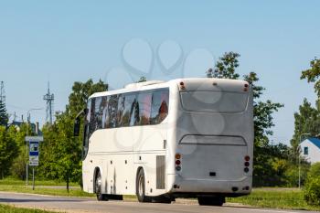 Rear view of white bus traveling on the road in a rural landscape