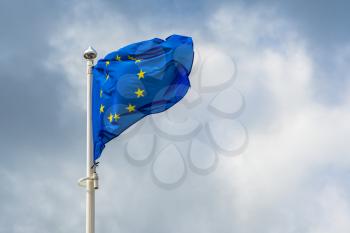 Blue flag of european union is waving on a background of stormy sky 