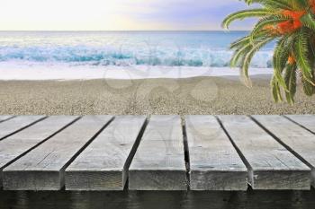 Wooden table near ocean beach with palm