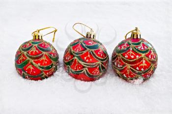 Three red with green, silver and gold ornaments Christmas ball on snow