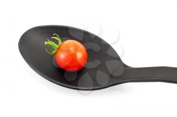 A small red tomato on a black plastic spoon isolated on white background