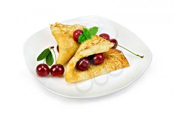 Two pancakes with berries cherries, mint on a white plate isolated on white background