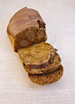 A loaf of sliced rye slices of homemade bread on the background of coarse sackcloth