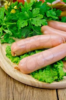 Wieners on a board with parsley and lettuce on a wooden boards background