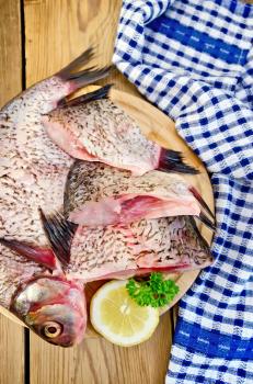 Bream whole peeled and sliced pieces on a round board, parsley, lemon, napkin on the background of wooden boards