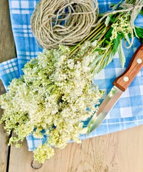 Bouquet of fresh flowers of meadowsweet with a knife and a coil of rope on a napkin on the background of wooden boards