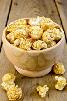 Caramel popcorn in a wooden bowl on a wooden boards background