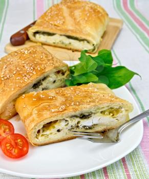 Roll layered with spinach and cheese, tomatoes in a plate on a linen tablecloth background