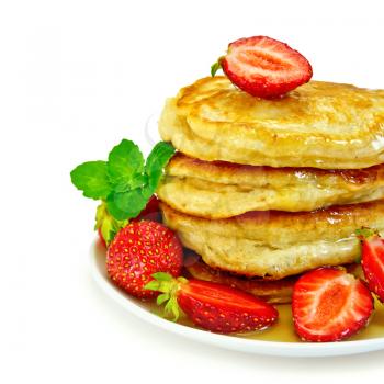 A stack of pancakes with strawberries, mint and honey on a white plate isolated on white background