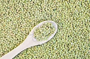 Texture of green lentils beans with wooden spoon