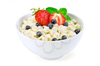 Cottage cheese in a white bowl with strawberries, blueberries and mint isolated on white background