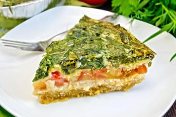 Celtic cake with spinach, tomatoes, oatmeal and eggs in a white plate in a baking dish from a foil, a napkin, parsley on a wooden boards background