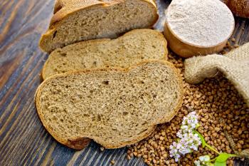 Slices of buckwheat bread, a bag of buckwheat, buckwheat flour, buckwheat flower on the background of wooden boards