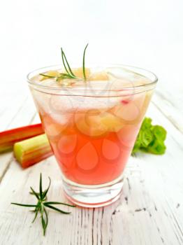 Lemonade with rhubarb and rosemary in a glass, the stems and leaves of rhubarb on the background light wooden boards