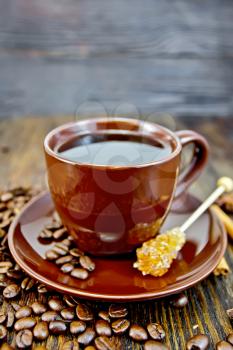 Coffee in cup brown with sugar, coffee beans and cinnamon sticks on a wooden boards background