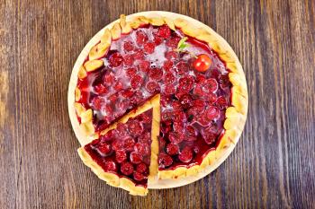 Round sweet pie with cherries and jelly on a wooden boards background