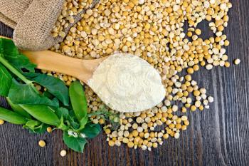 Flour pea in a spoon, yellow flakes in a bag and fresh pods on a background of wooden boards