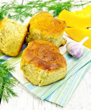 Pumpkin Scones with garlic and dill on a green towel, slices of pumpkin on a background of wooden boards