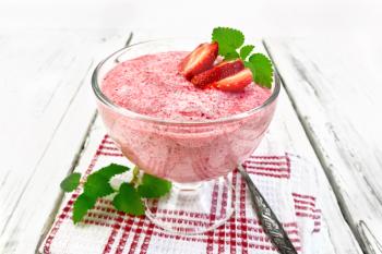 Jelly air strawberry sambuk in a glass bowl, mint and spoon on a napkin on a wooden board background