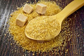 Sugar brown granulated in a spoon and cubes on a wooden board background