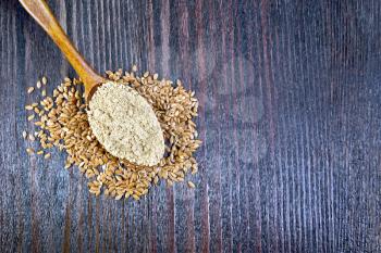 Flax flour in a spoon, seeds on a table on a background of a wooden board from above