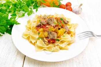 Macaroni Farfalle with turkey meat, tomato, yellow sweet pepper with sauce in a plate, garlic, parsley on a wooden board background