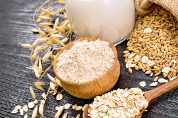 Flour in a bowl, grain in a bag, milk in a jug, oatmeal in a spoon, oaten stalks on wooden board background