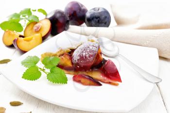 Piece of sweet pie with plum, sugar, cardamom in a plate, sprigs of green mint, a kitchen towel on wooden board background