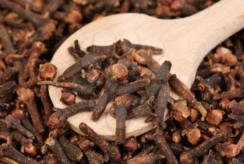 Cloves  (spice) and  wooden  spoon close-up food background 
