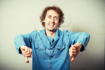 curly-haired man showing thumbs down