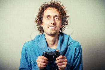 Curly young man playing video game winner. On a gray background
