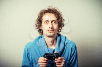 Curly young man playing video game winner. On a gray background