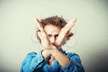 Curly young man gesture stop. On a gray background