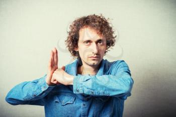 Curly evil man showing revenge hit in the palm fist. On a gray background.