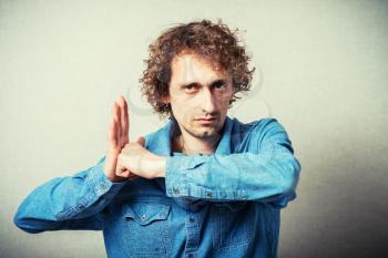 Curly evil man showing revenge hit in the palm fist. On a gray background.