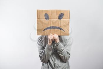 Young man standing with a cardboard on his head with sad face