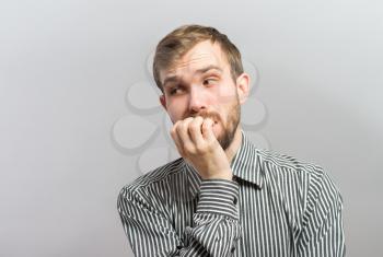 Closeup portrait of thinking man with finger in mouth, sucking thumb, biting fingernail in anxiety, stress, deep in thought, isolated on white background. Negative emotion, facial expression, feelings