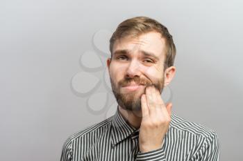 a young man with a beard in shirt feels toothache