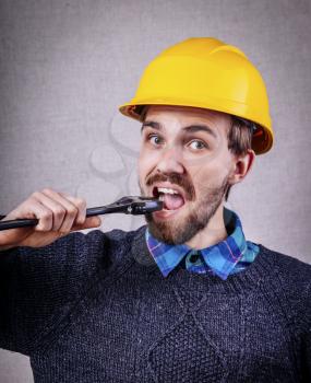 young construction worker with a wrench in the mouth