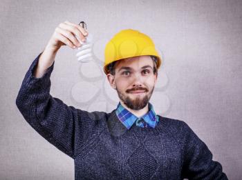 Young builder holding energy saving bulb