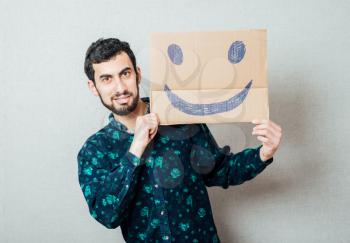 Businessman holding a cardboard smiley face emoticon in front of his head