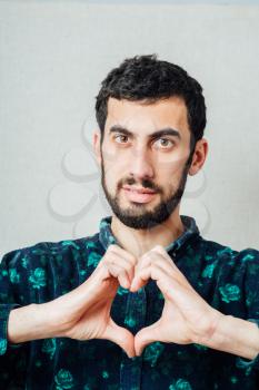 portrait of young man doing heart gesture