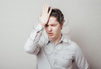 Closeup portrait of a upset young man with hand on his head