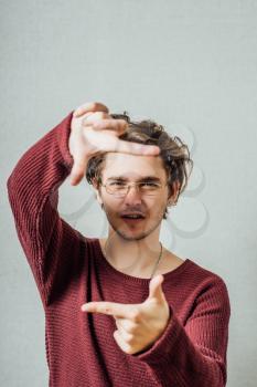 portrait of young man doing photo gesture over grey background