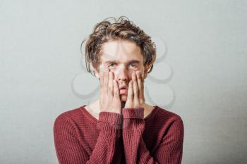 Closeup portrait, headshot young tired, fatigued business man worried, stressed, dragging face down with hands, isolated , grey background. Negative human emotions, facial expressions, feelings