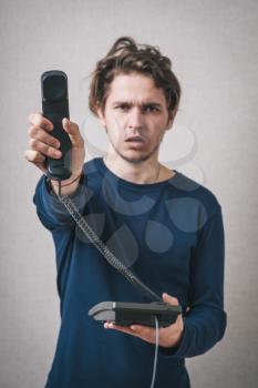 Young man with office or home phone. On a gray background.