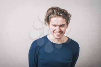 Young man laughing. Gray background.